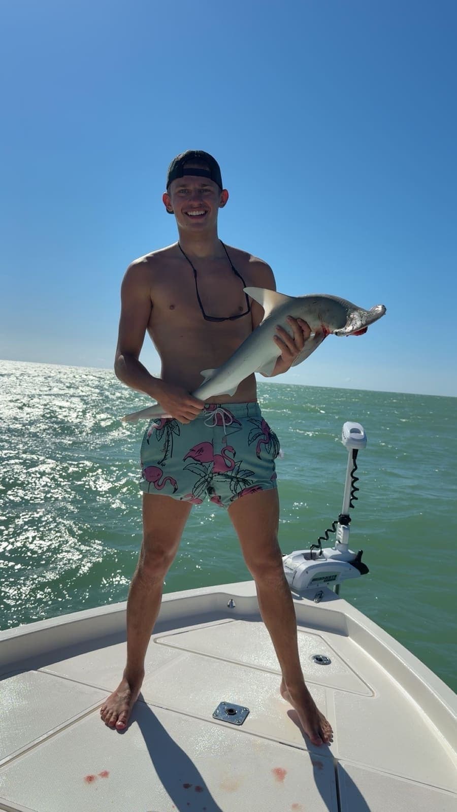 Guest standing on the bow holding a shark before release